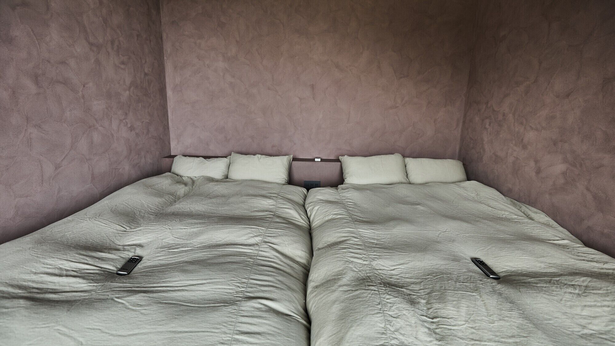 Cama doble con cabecera, dos almohadas y dos mesitas de noche con teléfonos.