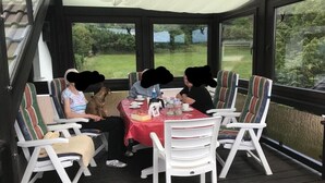Un'area salotto esterna riparata, con tavolo, sedie e un cane.