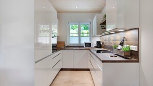 Una cocina moderna con armarios blancos, encimera de madera y ventana con vistas a zonas verdes.