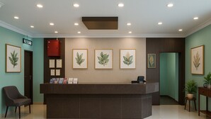 Un área de recepción con un mostrador oscuro, impresiones botánicas enmarcadas en la pared, un extintor rojo y un letrero que dice "KELDAR".