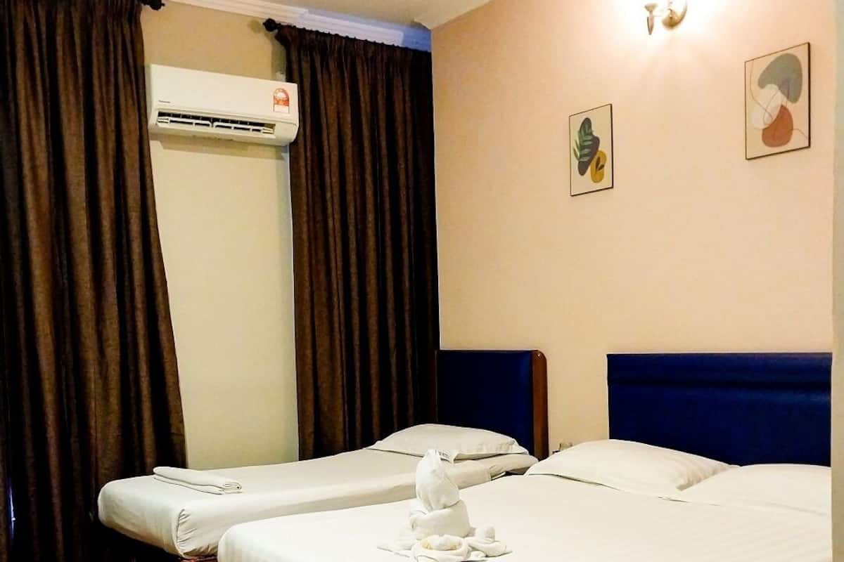 Habitación de hotel con dos camas, cortinas marrones, un aire acondicionado instalado en la pared y dos cuadros enmarcados.