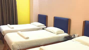 Habitación de hotel con cuatro camas individuales, aire acondicionado de pared y dos lámparas de pared.