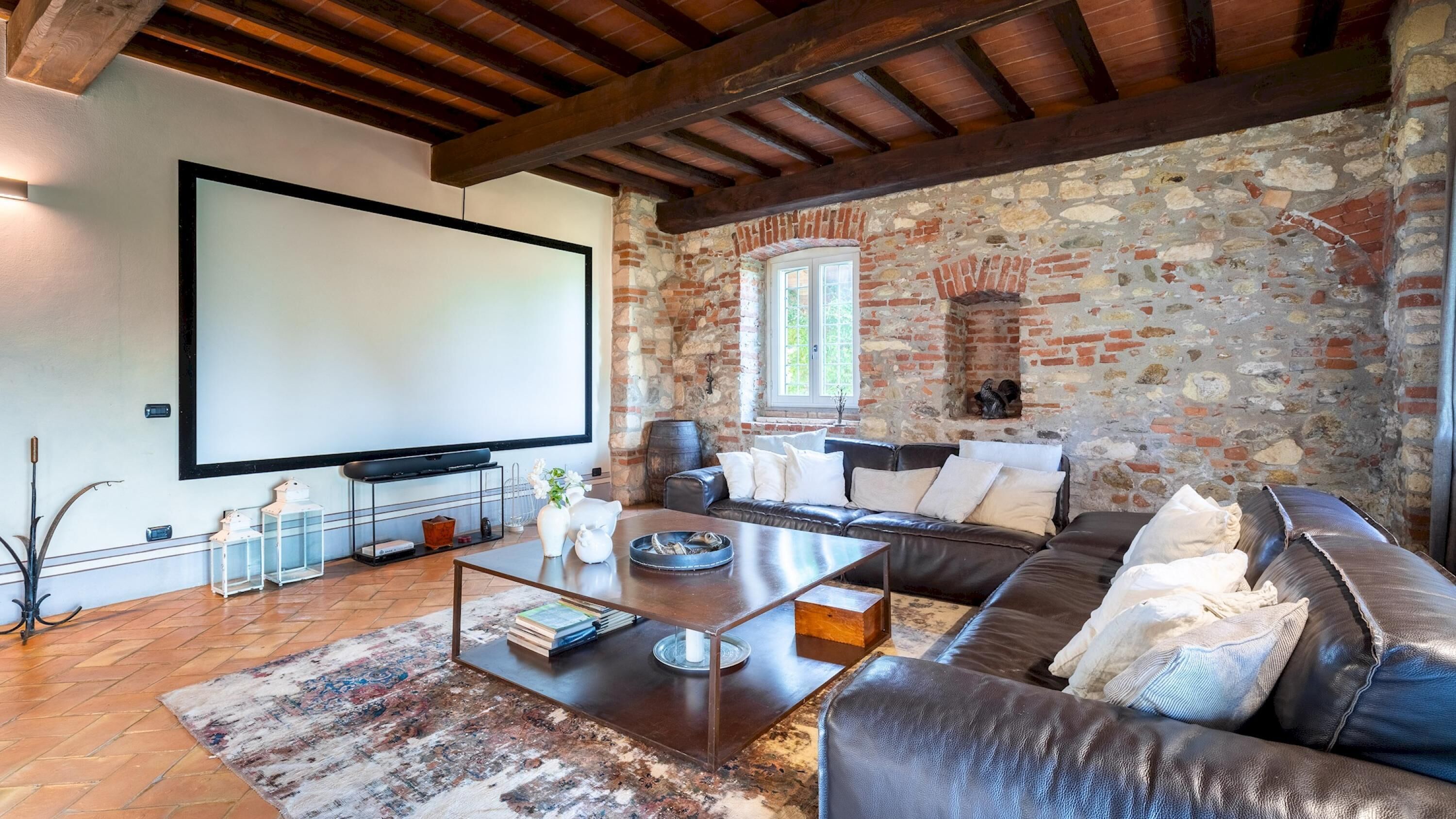 Una sala de estar acogedora con una pared de piedra, una chimenea, un sofá de cuero grande y un televisor de pantalla plana.