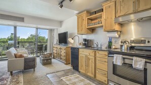 A modern kitchen with wooden cabinets, a built-in oven, and a large window overlooking a balcony.