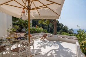 Eine Terrasse mit Gartenmöbeln, einem Essplatz und Meerblick.