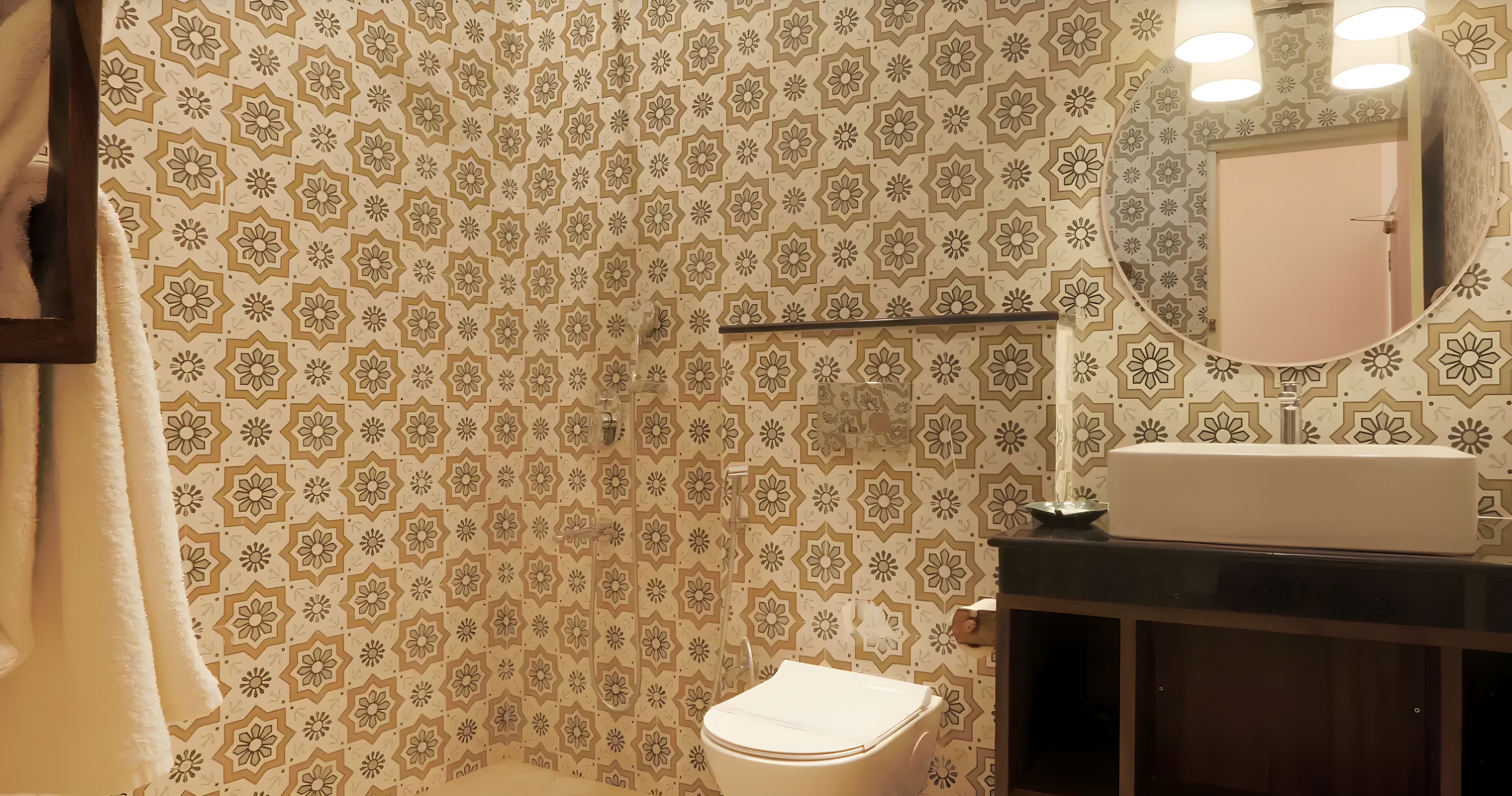 Een badkamer met behang met patroon, een toilet, een wastafel met spiegel en een handdoek aan de muur.