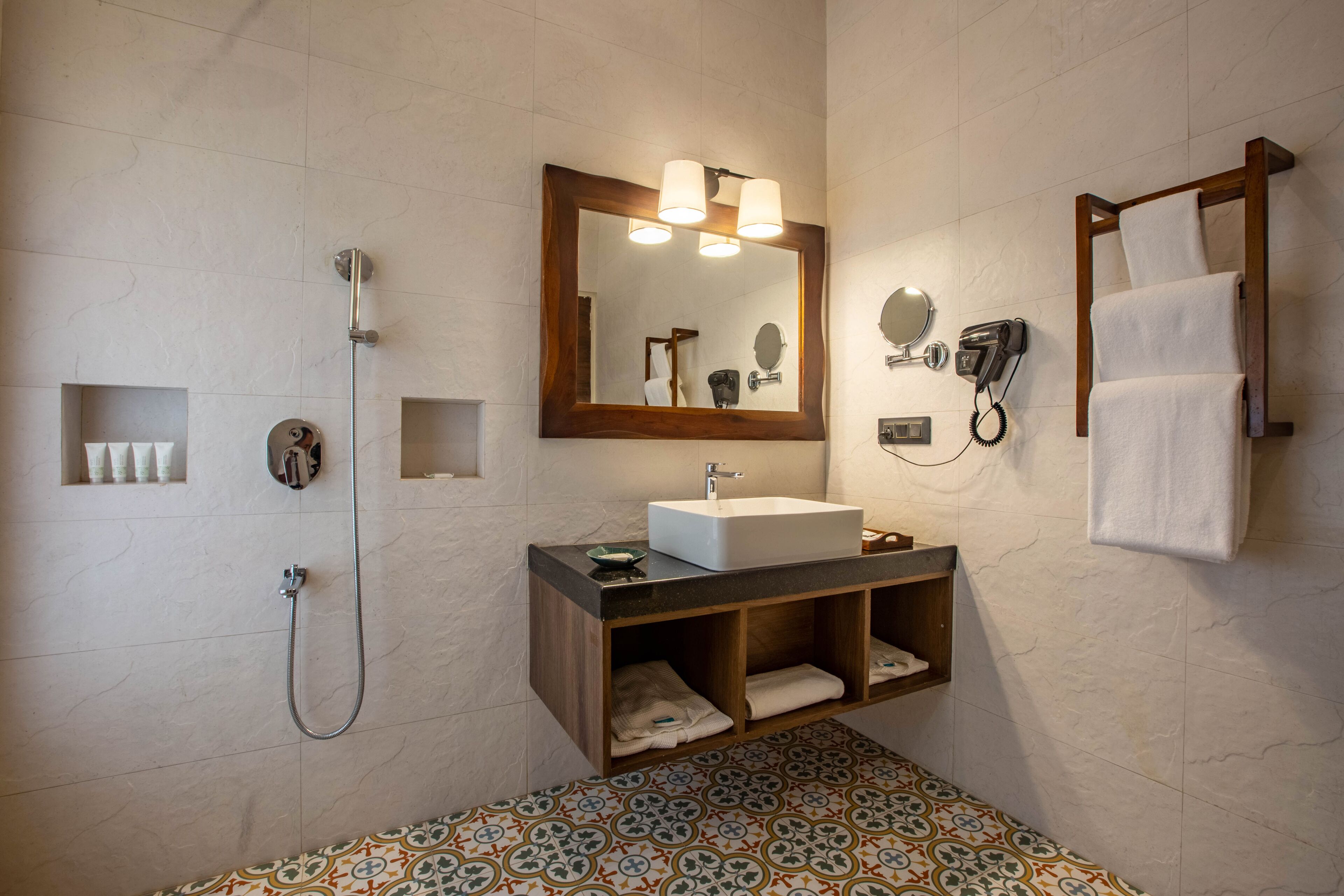 A bathroom with a large mirror, a sink, a shower, a towel rack, and a telephone.