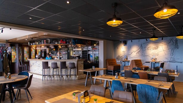 A restaurant with a bar area, multiple tables and chairs, and a wall with a map. - luxury chalet on a cosy campsite near the sea (Westerland)
