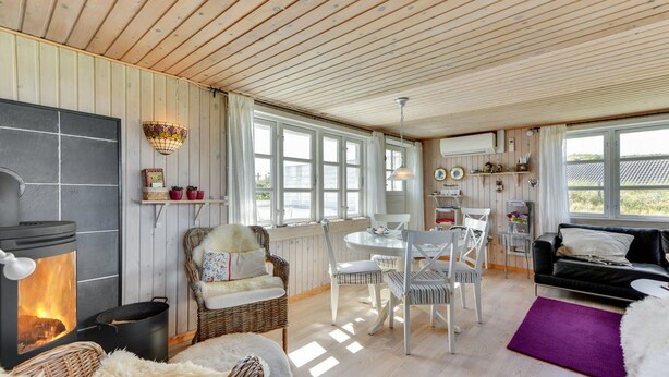 Ein gemütliches Blockhaus-Interieur mit Kamin, Korbmöbeln und einem Essbereich.