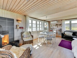 Un interior de cabaña acogedor con chimenea, muebles de mimbre y un comedor.