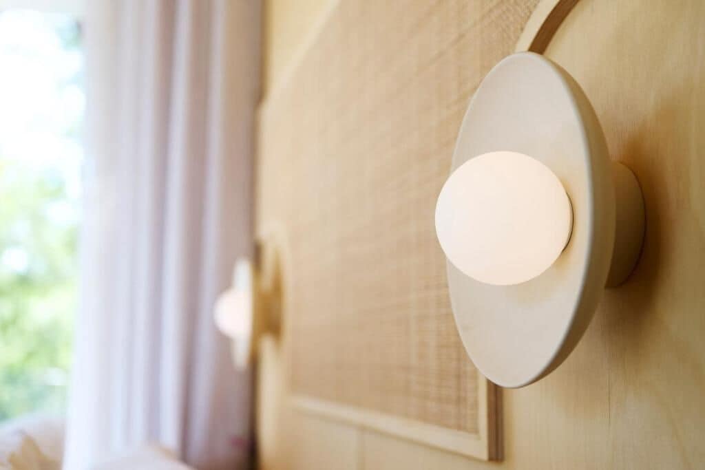 Eine wandmontierte Leuchte mit kreisförmigem Design, angebracht an einer hellen Wand mit Struktur.