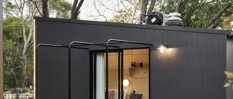 Eine kompakte, moderne Holzhütte mit einer Schiebetür zu einem gemütlichen Innenraum.