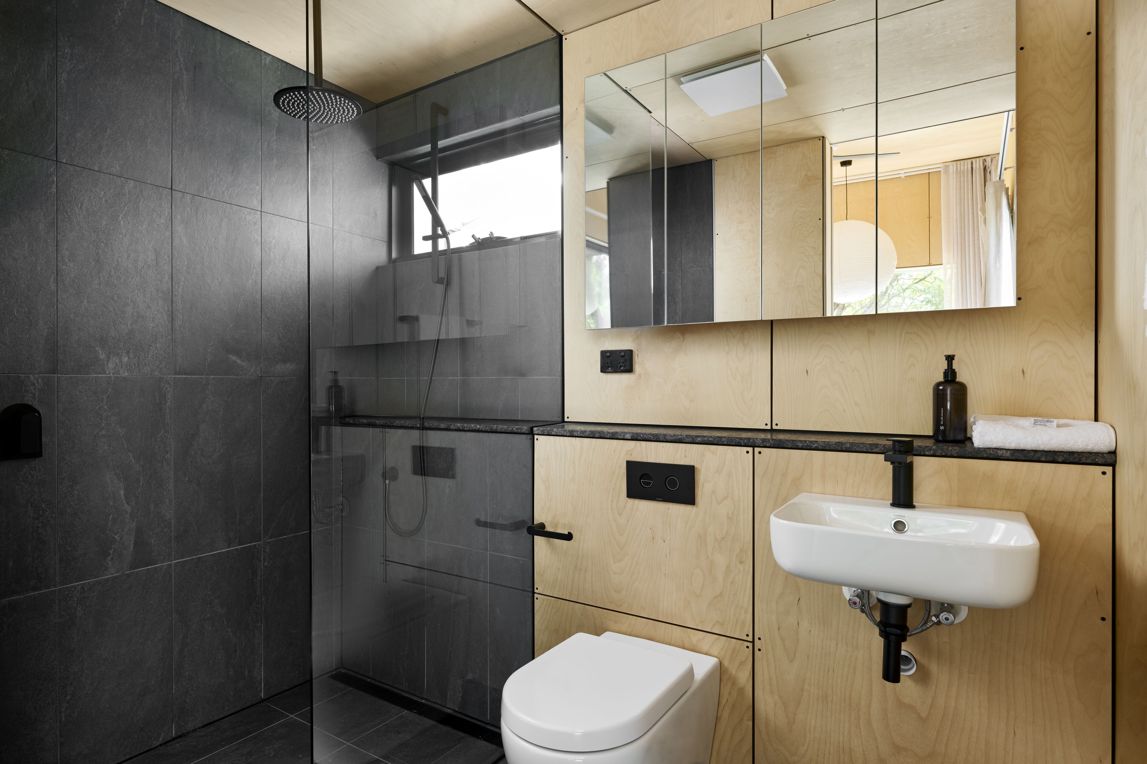Ein modernes Badezimmer mit einer Glaskabinentasse, einer weißen Toilette und einem Holzwaschtisch.
