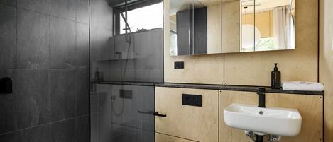 Ein modernes Badezimmer mit einer Glaskabinentasse, einer weißen Toilette und einem Holzwaschtisch.