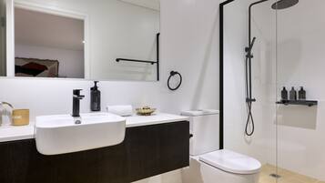 A modern bathroom with a white sink, dark vanity, and a glass-enclosed shower.