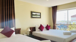 Une chambre d’hôtel avec deux lits, une table de chevet avec une lampe, un téléphone et un tableau encadré au mur.