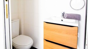 Et lille badeværelse med toilet, et træbord med spejl og et håndklæde hængende på væggen.