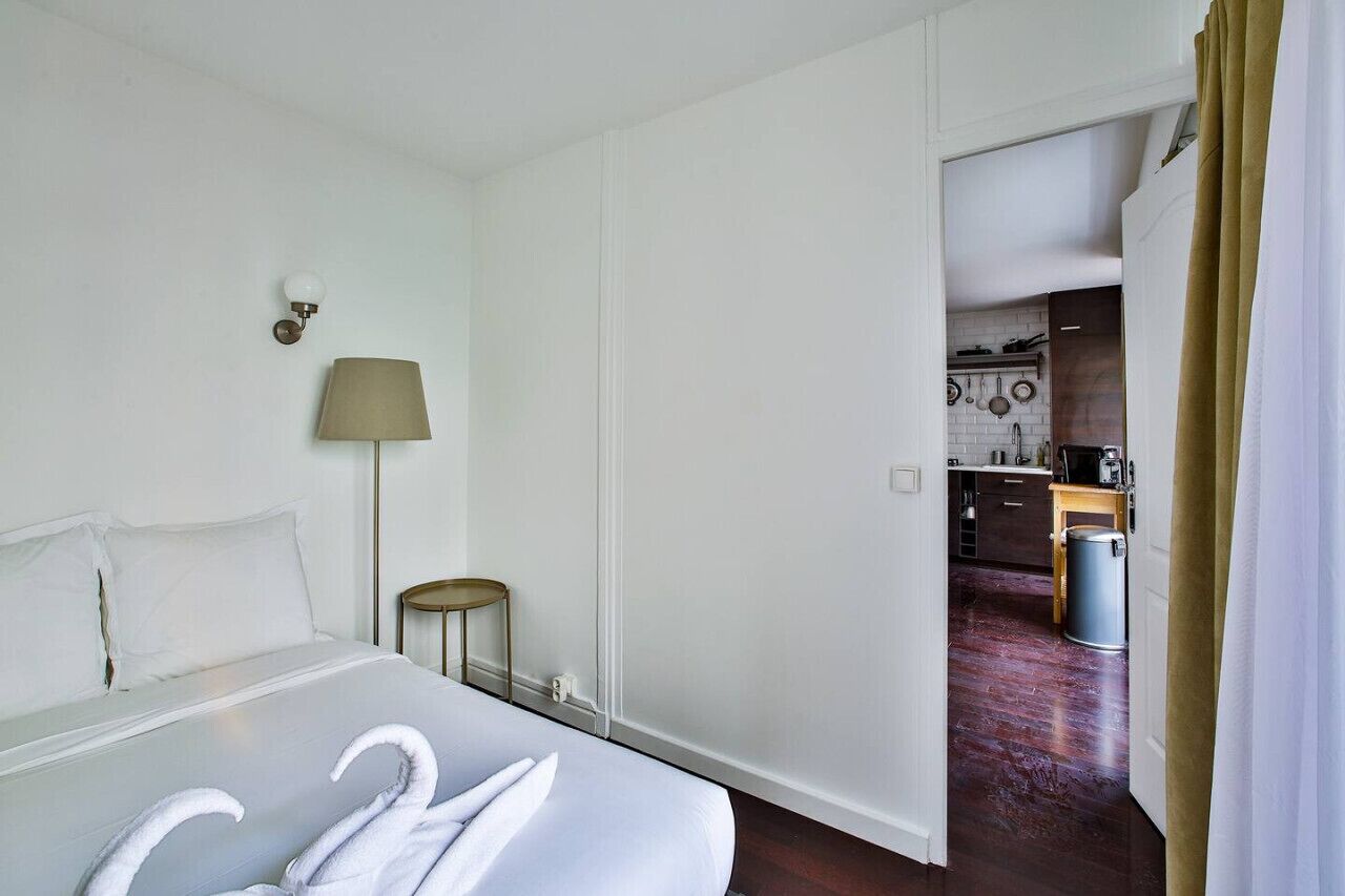 Habitación de hotel con cama, lámpara y vistas a la cocina.