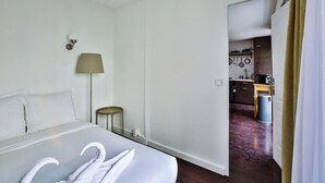 A hotel room with a bed, a lamp, and a view into the kitchen. - Appart 4pers#St Antoine#Bastille#Nation (Paris)
