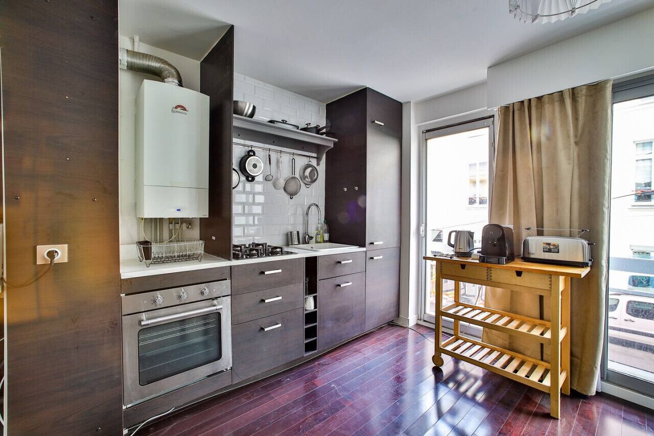Een moderne keuken met een inbouwoven, een koffiezetapparaat en een broodrooster op een houten tafel.