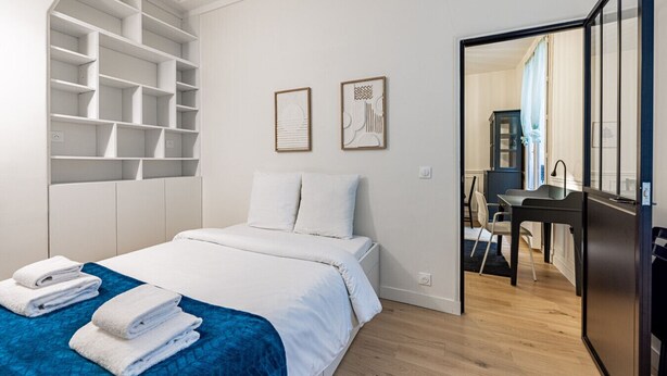 A modern hotel room with a bed, a desk, and a walk-in closet. - Au cœur des Batignolles (Paris)