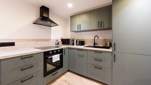 A modern kitchen with grey cabinets, a black stove, and a stainless steel range hood. - 1 Bedroom#4 pers#Mouffetard#Port-Royal#La Sorbonne (Paris)