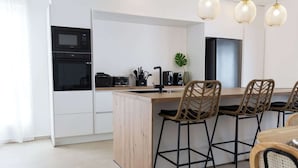 Una cocina moderna con una isla central, taburetes de bar y una mesa de comedor.