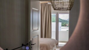 Un dormitorio con cama, ventana con cortinas y vista a zonas verdes.