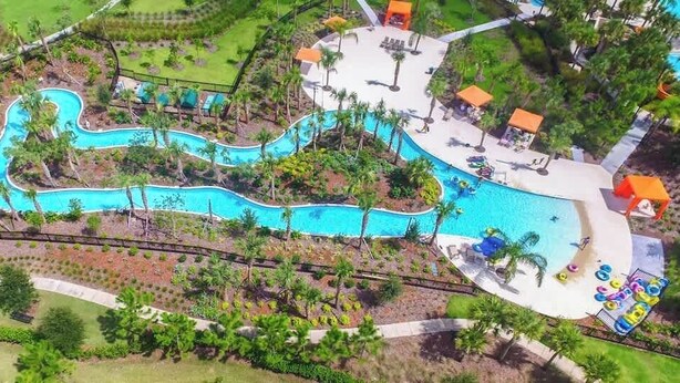 An aerial view of a resort with a winding pool, palm trees, and a children's play area. - 6BD Solterra Resort Near Disney (ST 5113) (Davenport)