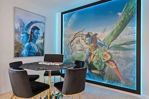 A room with a large digital art display, a round table with chairs, and a laptop on the table. - 6BD Solterra Resort Near Disney (ST 5113) (Davenport)
