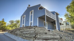 A two-story house with a stone retaining wall and a wooden deck. - Mid-Good Day Venture (Colorado Springs)