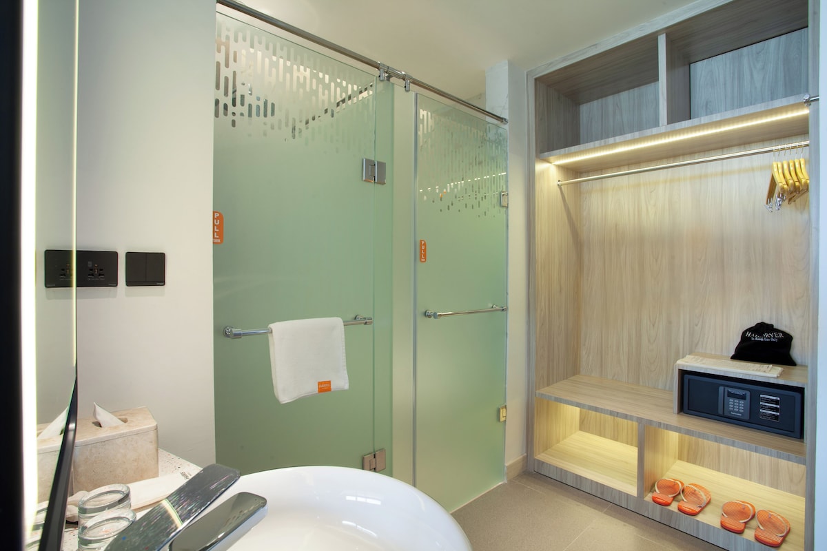 Une salle de bain moderne avec une douche à parois de verre, une baignoire blanche et un meuble-lavabo en bois équipé d’un micro-ondes.