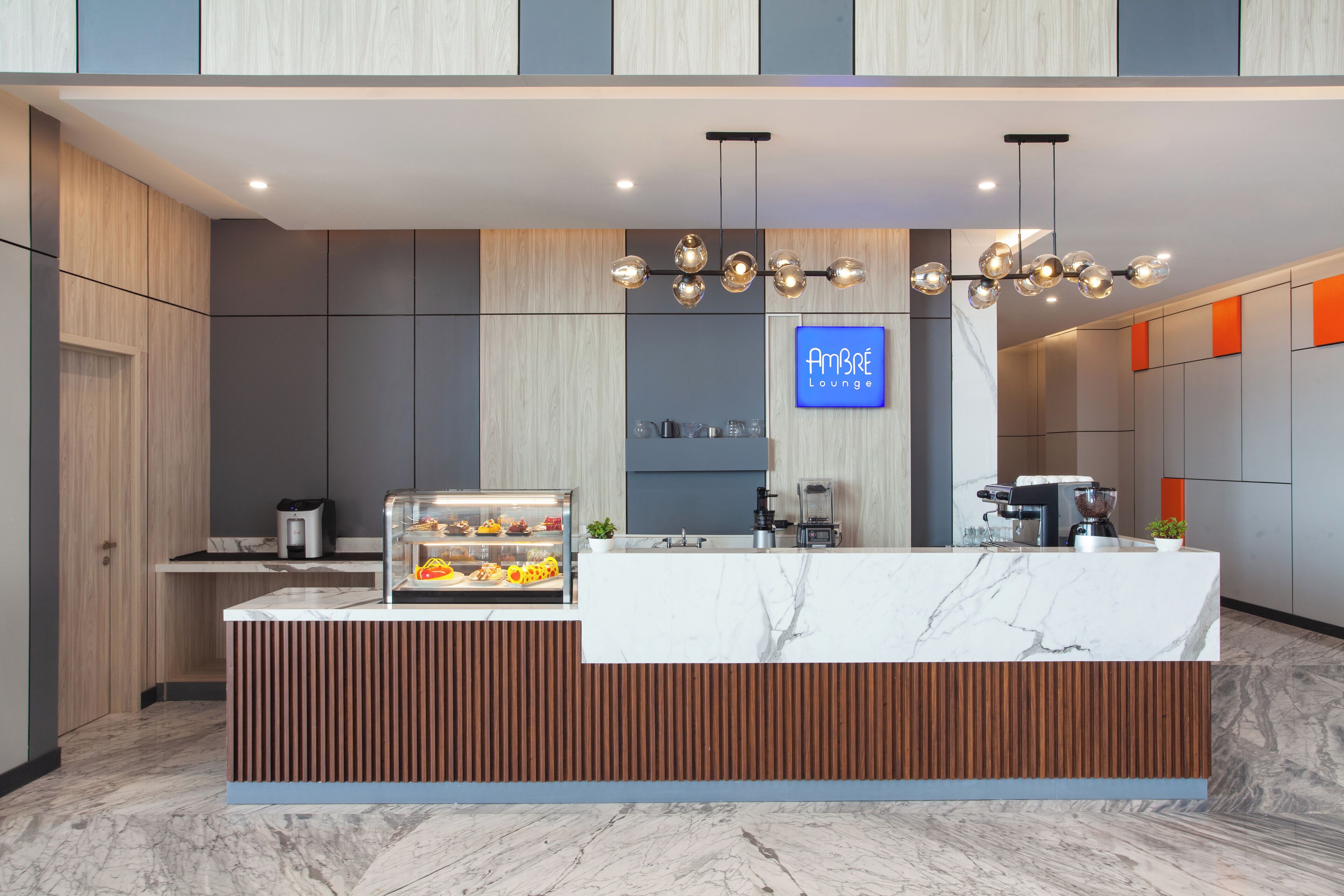 A modern reception area with a marble counter, wooden paneling, and a sign reading "Ambre Lounge".