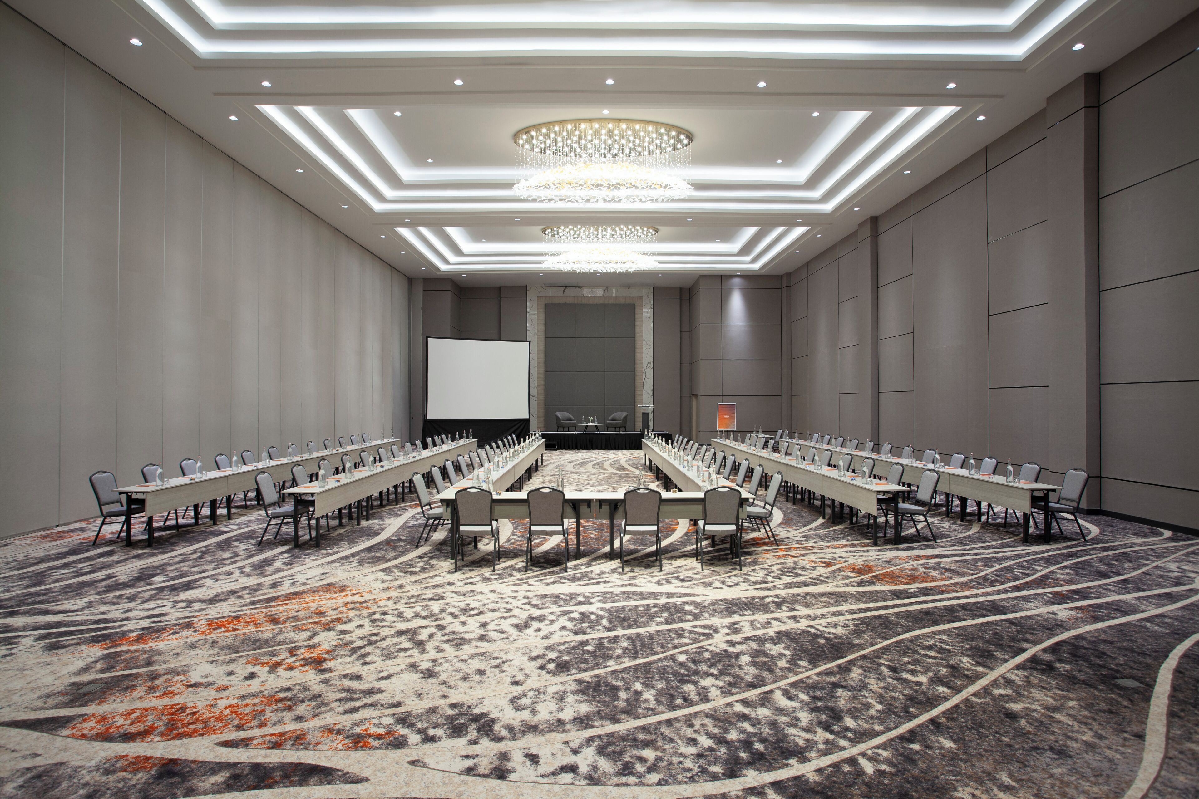 A conference room with a long table, chairs, and a projector screen.