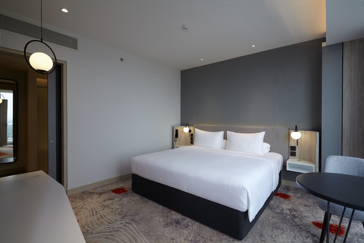 Une chambre d’hôtel moderne, dotée d’un grand lit, de tables de chevet, d’un bureau et d’une chaise.