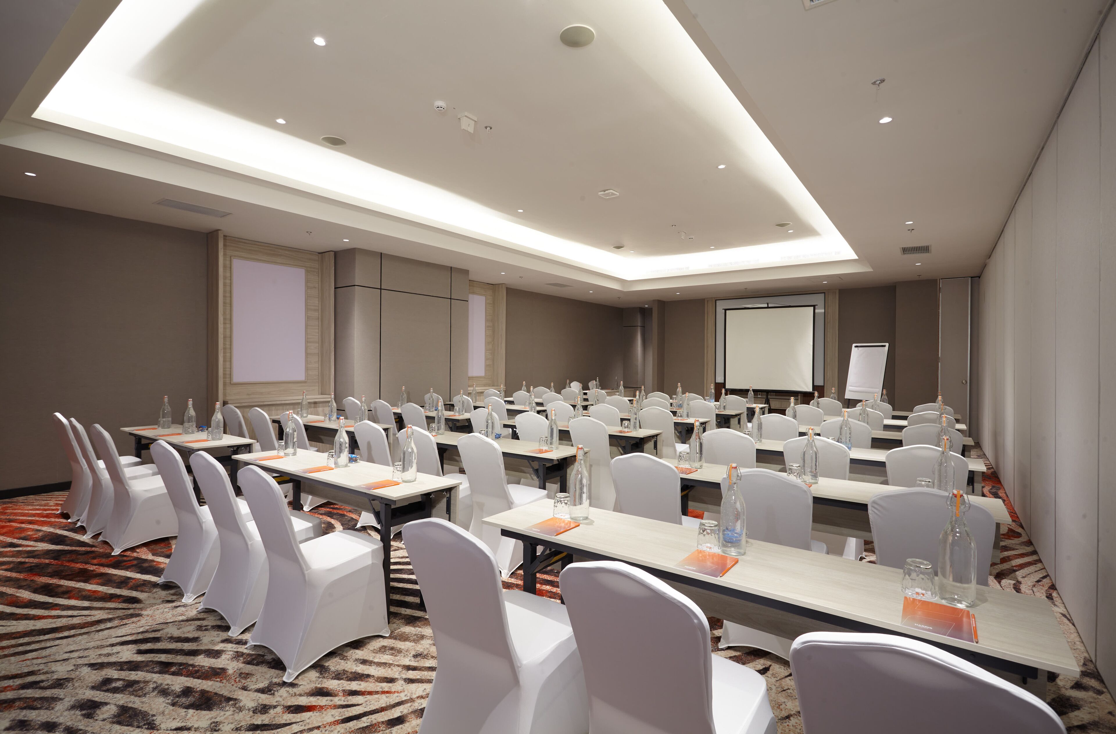 A conference room with tables and chairs, equipped with water bottles and glasses.