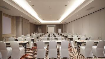 Un salón de conferencias con varias mesas y sillas, equipado con botellas de agua y tarjetas de identificación.