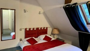Een slaapkamer met een bed, een spiegel, een nachtkastje en een raam met gordijnen.