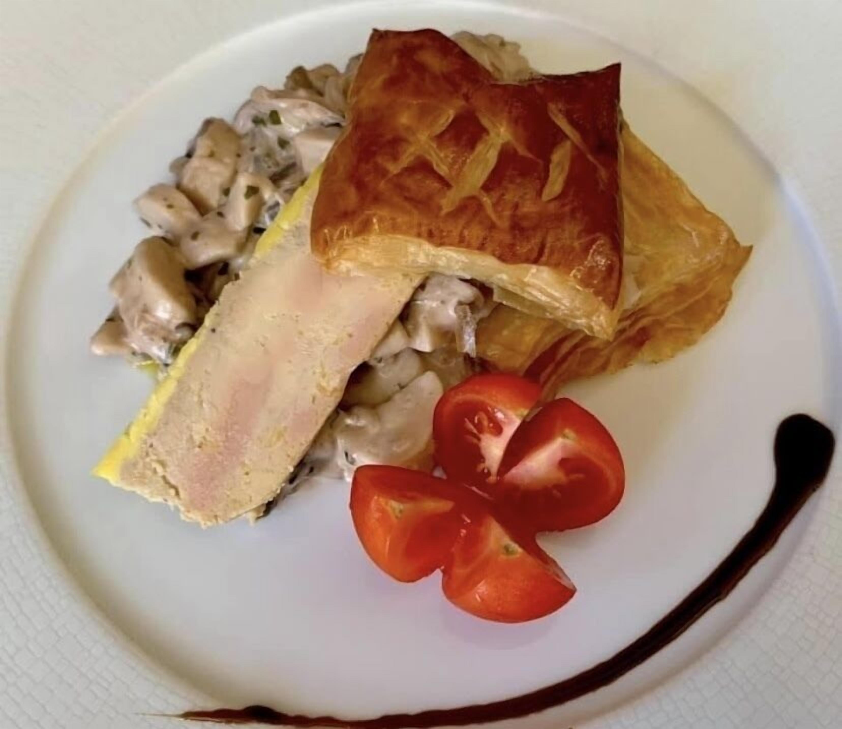 Une assiette avec une tranche de viande, une pâtisserie et quelques légumes.