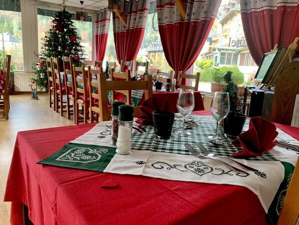 A dining area with a table set for two, featuring a red tablecloth, white napkin, and a green placemat.