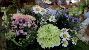 Een kamer met een groot raam, houten balken en een tafel met een bloemstuk.
