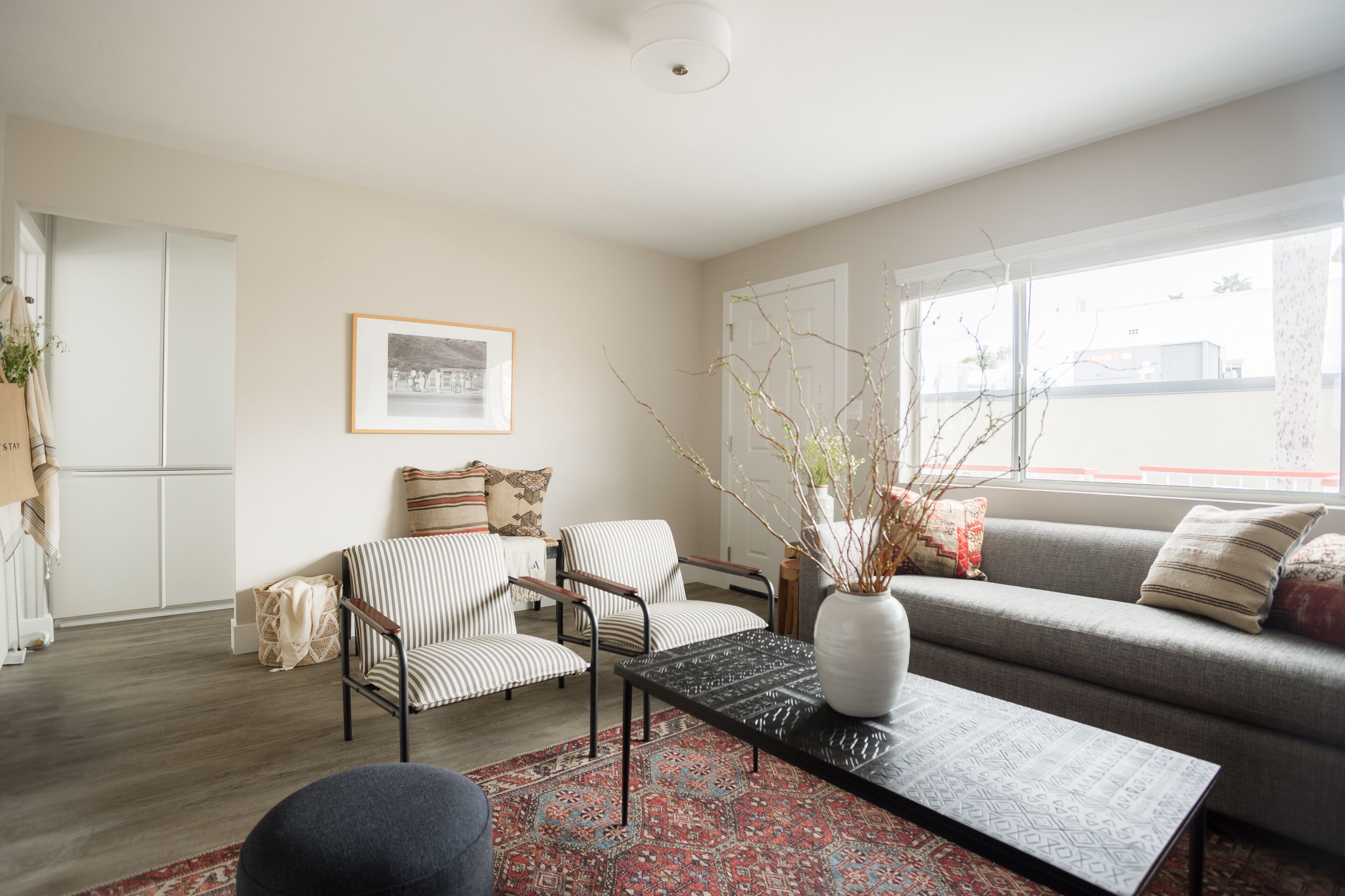 Un salon comprenant un canapé, deux fauteuils à rayures, une table basse et un tableau encadré accroché au mur.