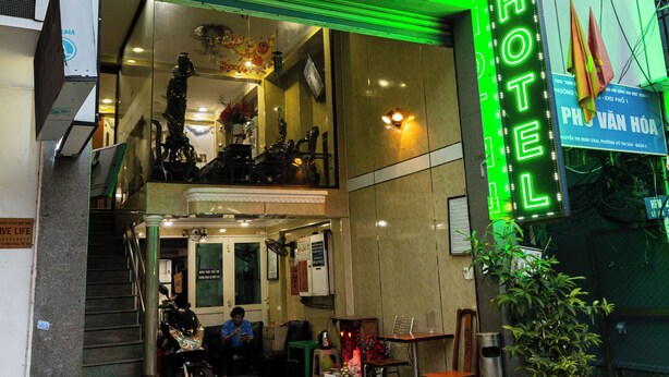 A hotel entrance with a neon sign, a staircase, and a motorcycle parked outside. - Vuon Tao Dan Hotel Near Ben Thanh Market (Ho Chi Minh City)