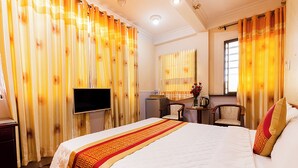 A hotel room with a large bed, a television, a desk with a chair, and curtains. - Vuon Tao Dan Hotel Near Ben Thanh Market (Ho Chi Minh City)