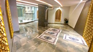 Un interior moderno con suelo de mármol, patrones geométricos en la pared e iluminación empotrada.