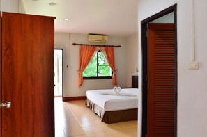 A hotel room with a bed, a window with curtains, and an air conditioning unit. - Heimat Garden (Ko Yao)