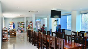 A spacious dining area with a long wooden table and chairs, surrounded by shelves stocked with various items. - Heimat Garden (Ko Yao)