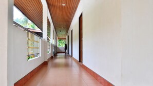 A long, narrow corridor with tiled flooring, wooden ceiling beams, and windows with metal bars. - Heimat Garden (Ko Yao)