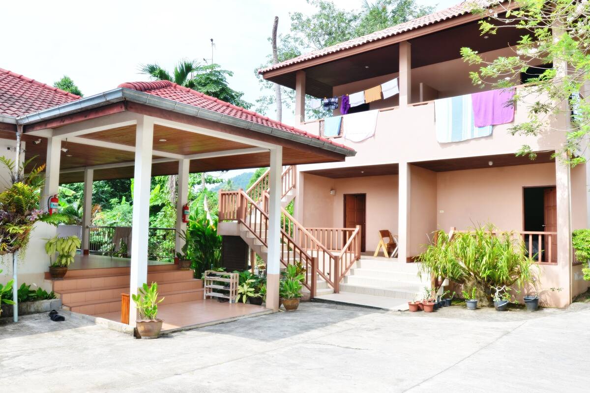 A two-story house with a covered porch, a staircase, and potted plants.