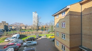 A parking area with multiple cars and a building with a brick facade. - London Oasis in Woolwich Arsenal  (London)